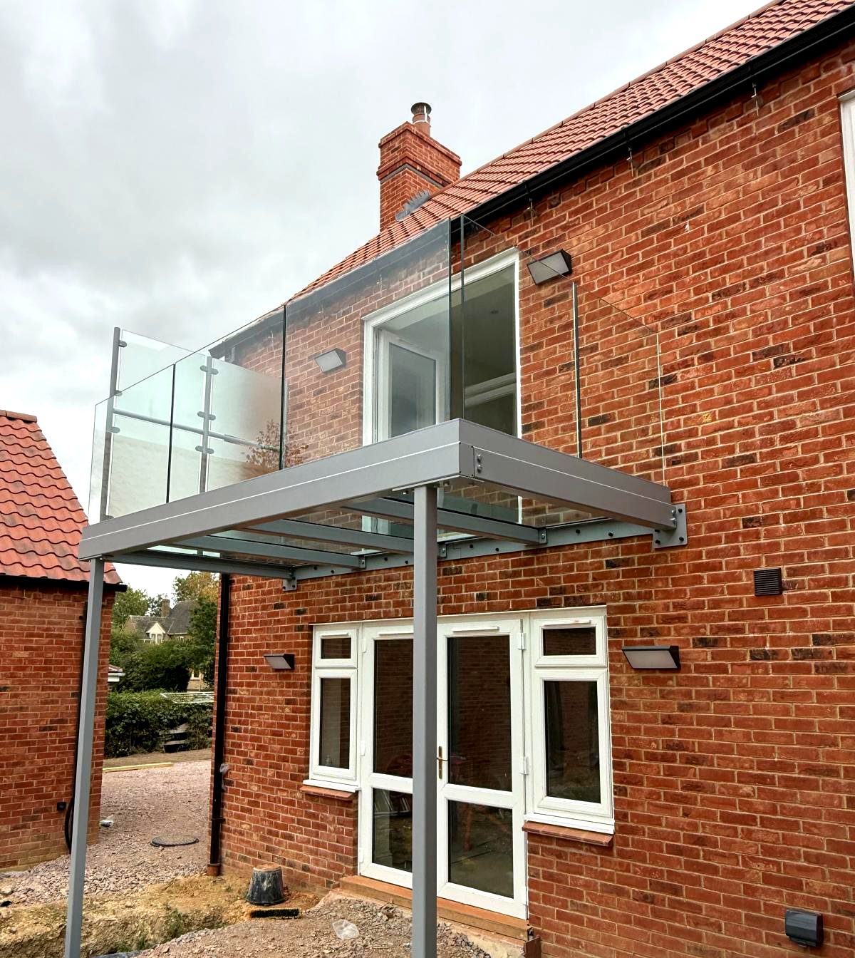 Steel support posts and glass floor of a walkout balcony over ground floor doors, Rutland